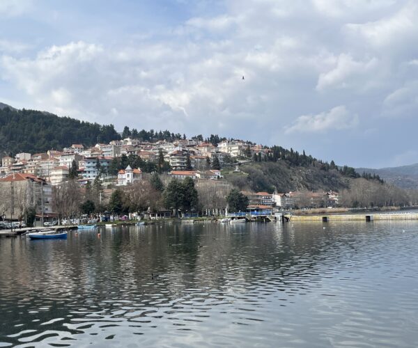 kastoria-panorama-ezero-orestiada.jpg Панорамна гледка към Кастория с къщи по хълма и лодки в езерото Орестиада